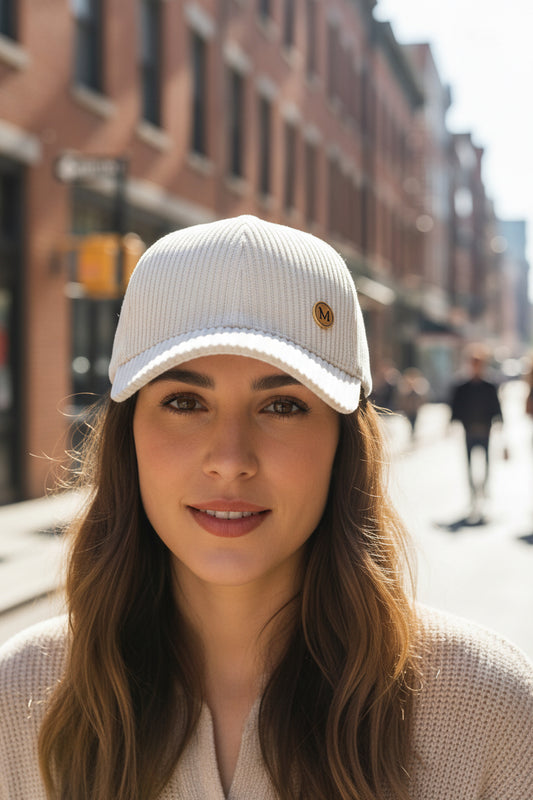 A beige corduroy baseball cap with a metal letter M on the front.