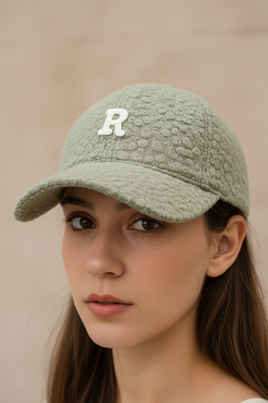 A beige baseball cap with a large 'R' letter embroidered on the front.