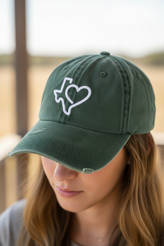 Green cap with a white heart and Texas outline design on a wooden surface
