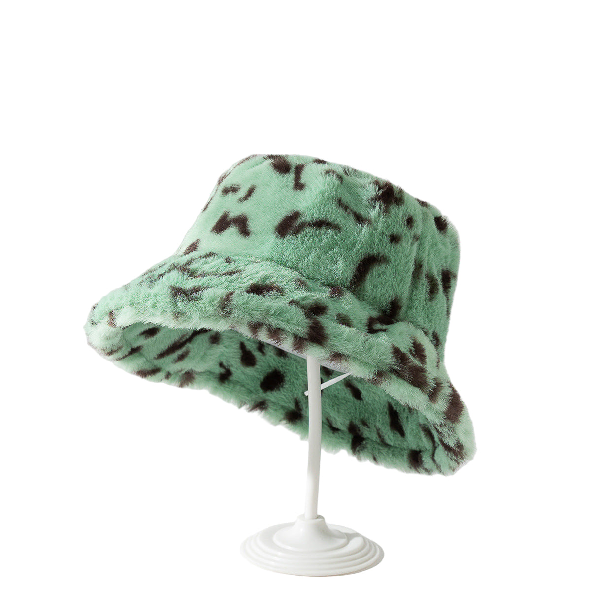Green fuzzy hat with brown spots on a white stand against a light gray background