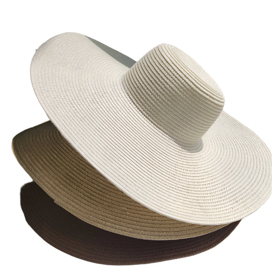 Two straw hats, one beige and one brown, on a light surface with a blue background.