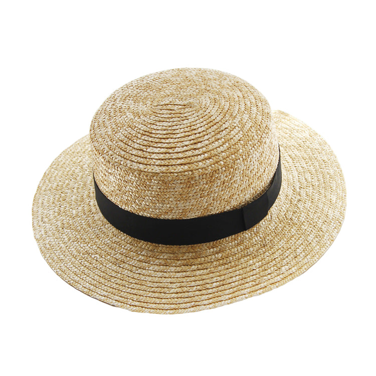 Straw hat with a black band on a white surface