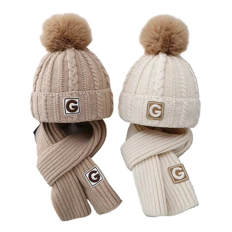 Two knitted hats with pom-poms and scarves on a chair, featuring a brand logo.