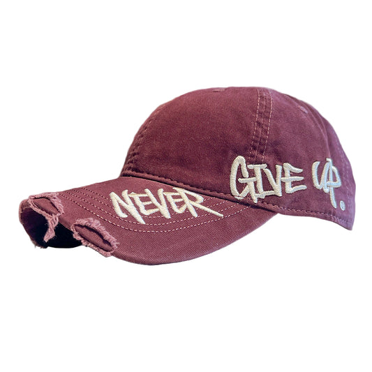 Maroon cap with 'Never Give Up' text on a blurred indoor background
