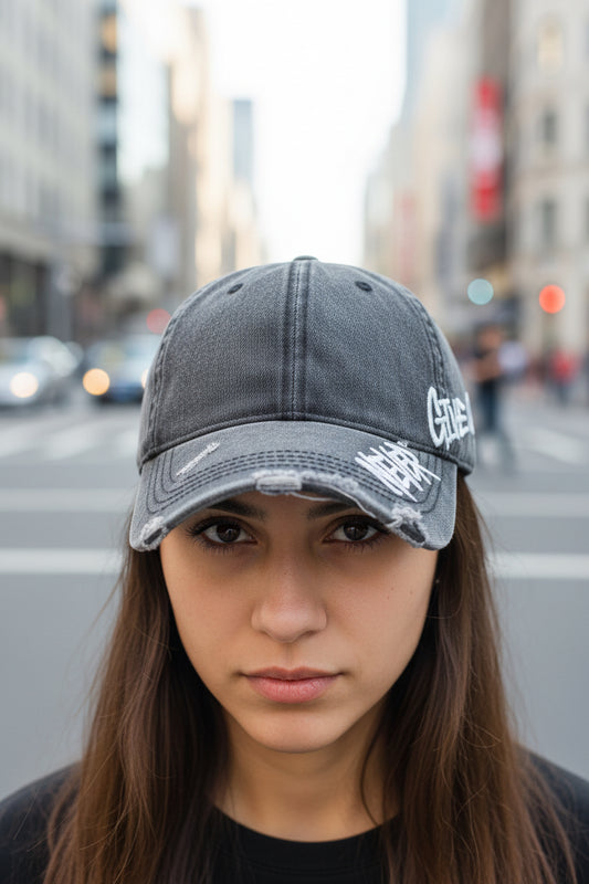 Gray denim cap with 'Never Give Up' text on a blurred indoor background
