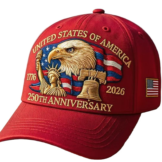 Red cap with American-themed design featuring an eagle, Statue of Liberty, and Liberty Bell on a wooden surface.