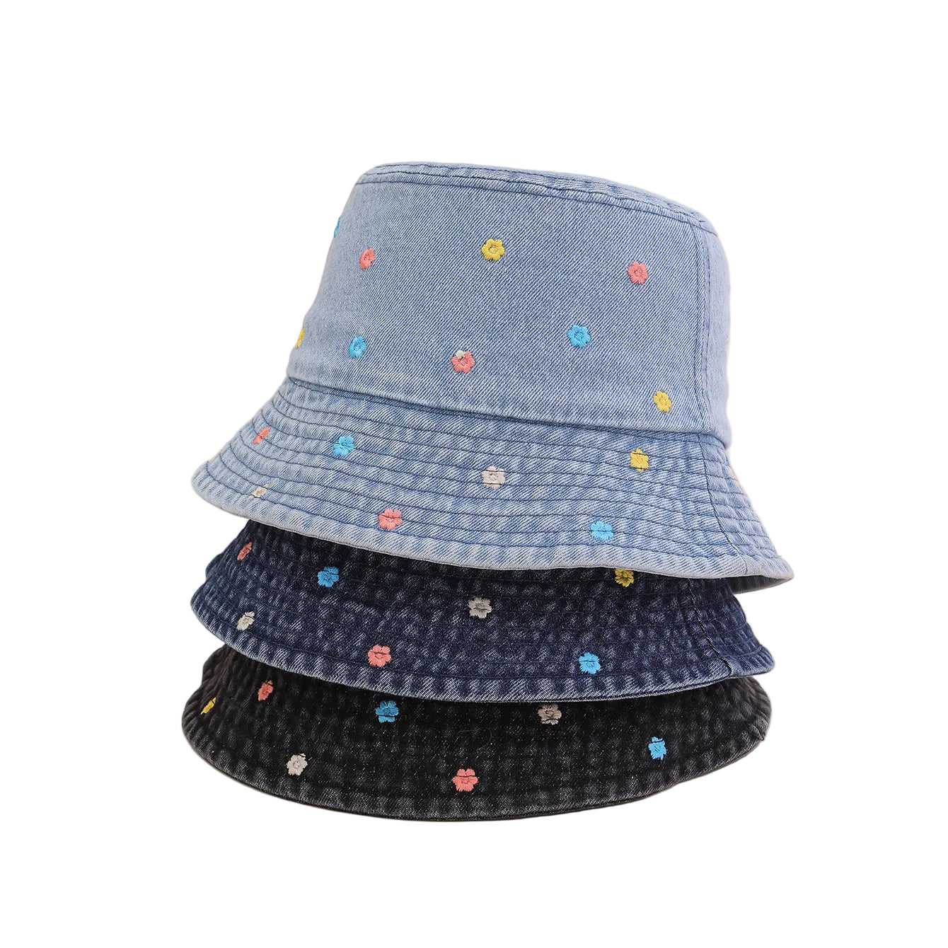 Stack of denim bucket hats with embroidered flowers on a beige background
