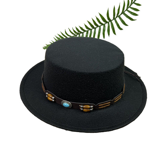 Black hat with decorative band on a wooden surface