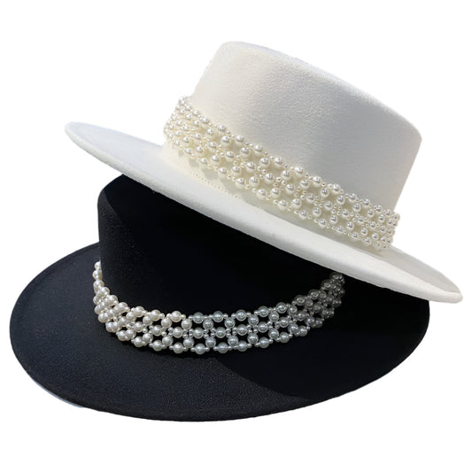 Two hats, one white and one black, with pearl bands on a reflective surface.